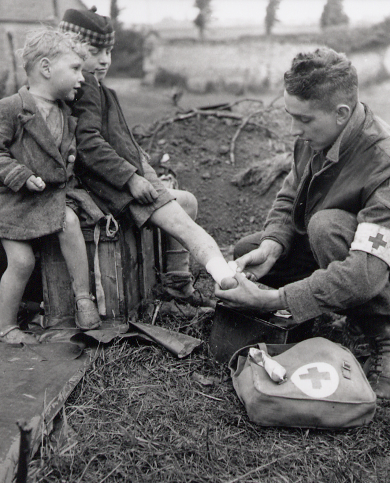 Vimy to Juno thumbnail featuring a black and white photo of a wartime medic bandaging a young boy’s injured leg while another small boy watches